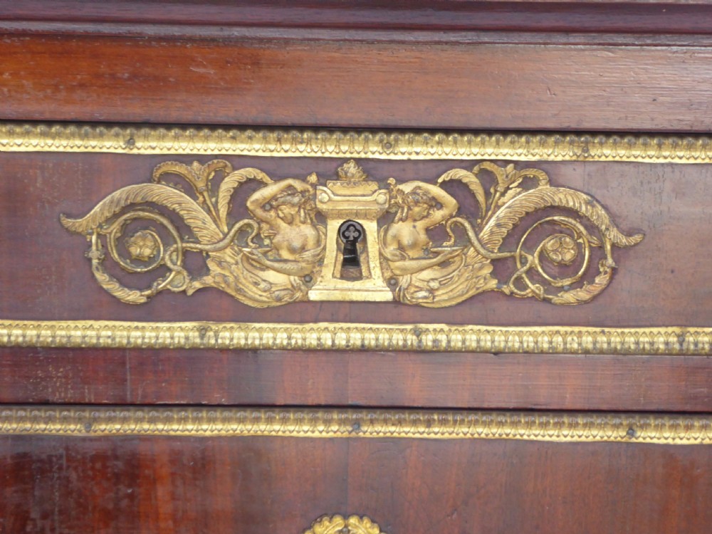 A dark mahogany drop-front escritoire cabinet featuring an open writing flap, fitted interior drawers, brass mounts, a black marble top, and carved paw feet. View VII