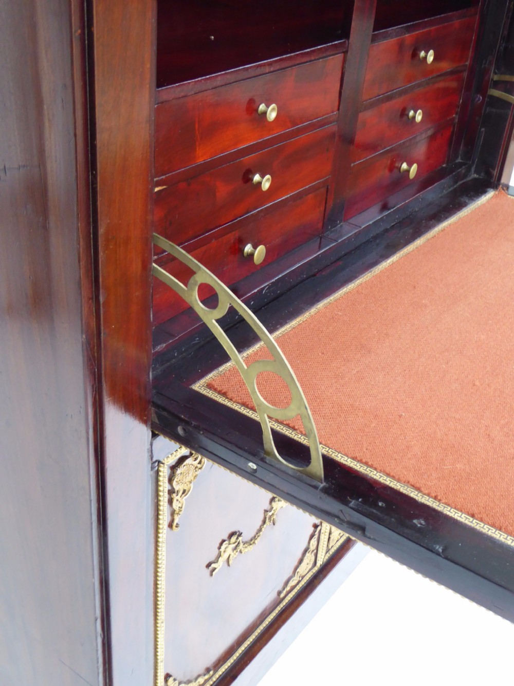 A dark mahogany drop-front escritoire cabinet featuring an open writing flap, fitted interior drawers, brass mounts, a black marble top, and carved paw feet. View XII
