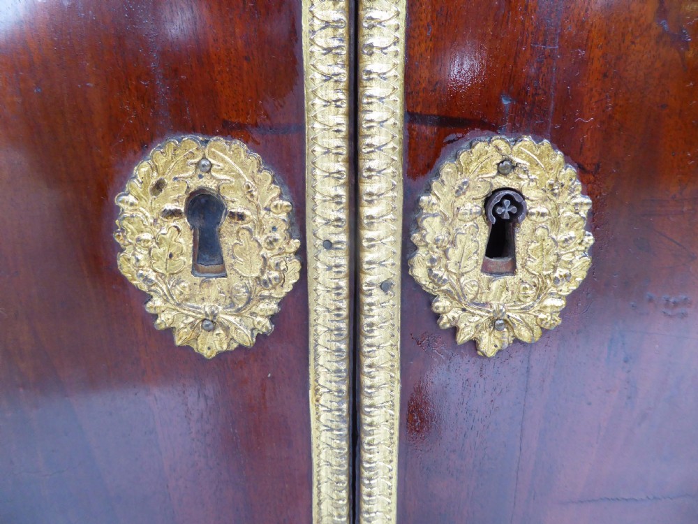 A dark mahogany drop-front escritoire cabinet featuring an open writing flap, fitted interior drawers, brass mounts, a black marble top, and carved paw feet. View XVII