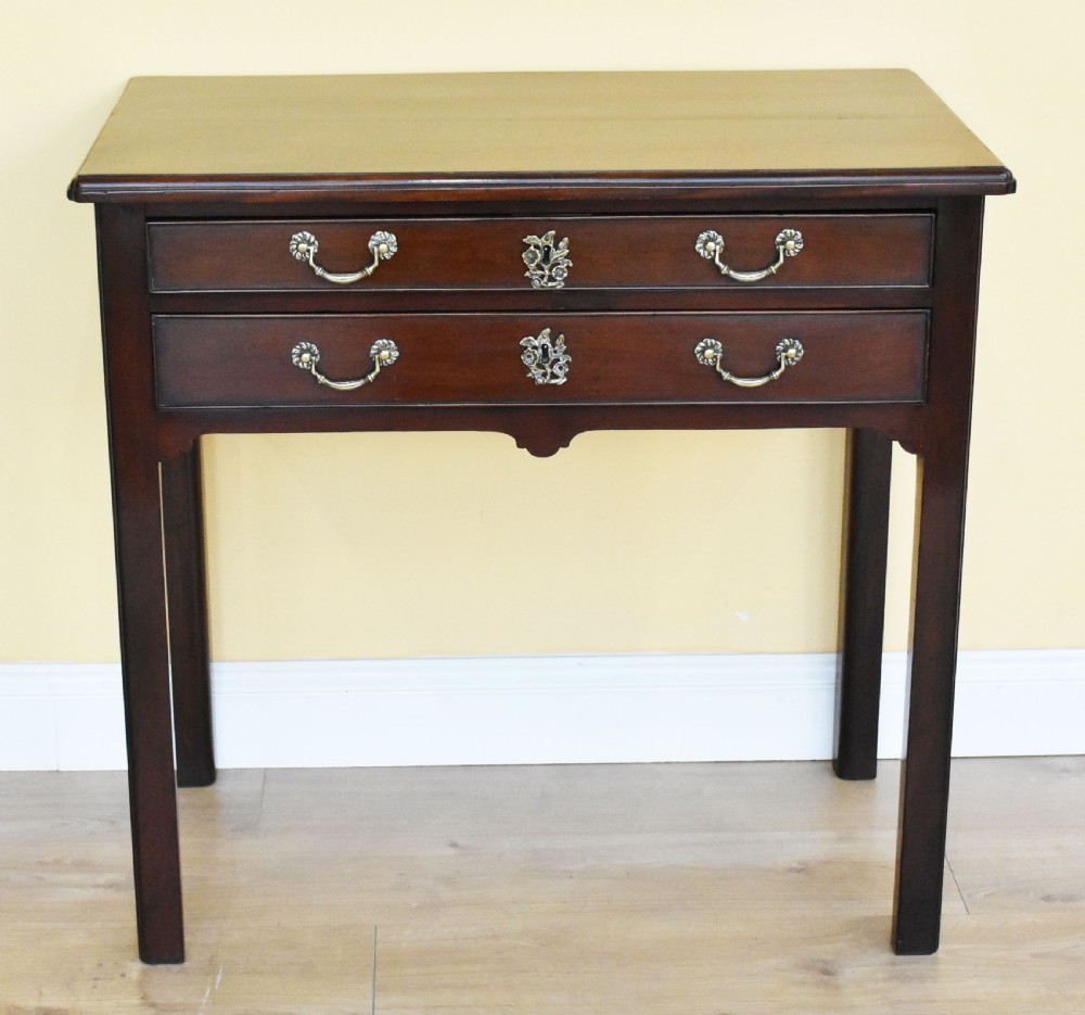 A George III mahogany side table featuring two drawers with brass swan-neck handles and decorative keyhole escutcheons, supported on straight square legs. View II