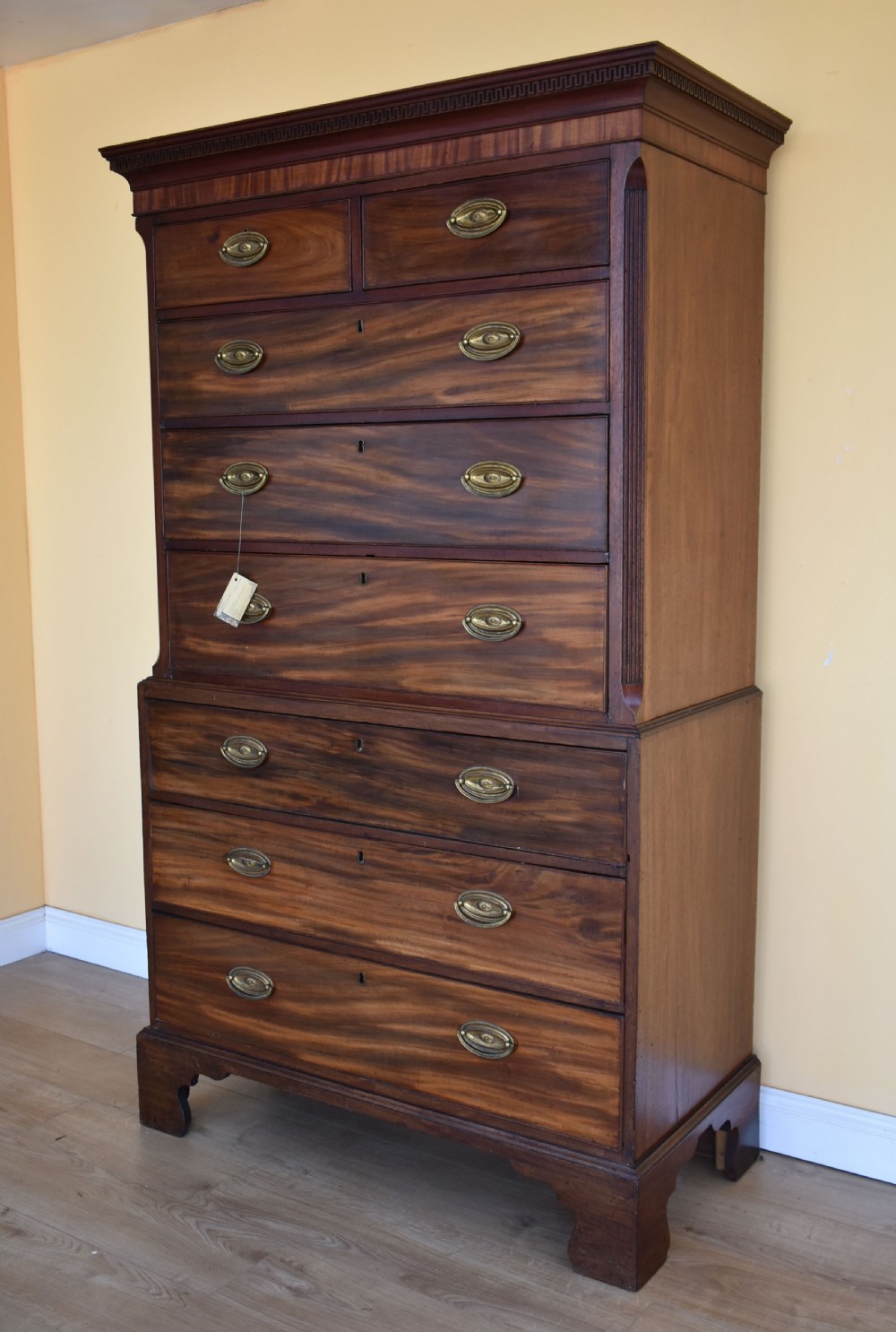 A George III mahogany chest-on-chest featuring a dentil-moulded cornice, fluted chamfered corners, brass oval handles, and bracket feet. View II