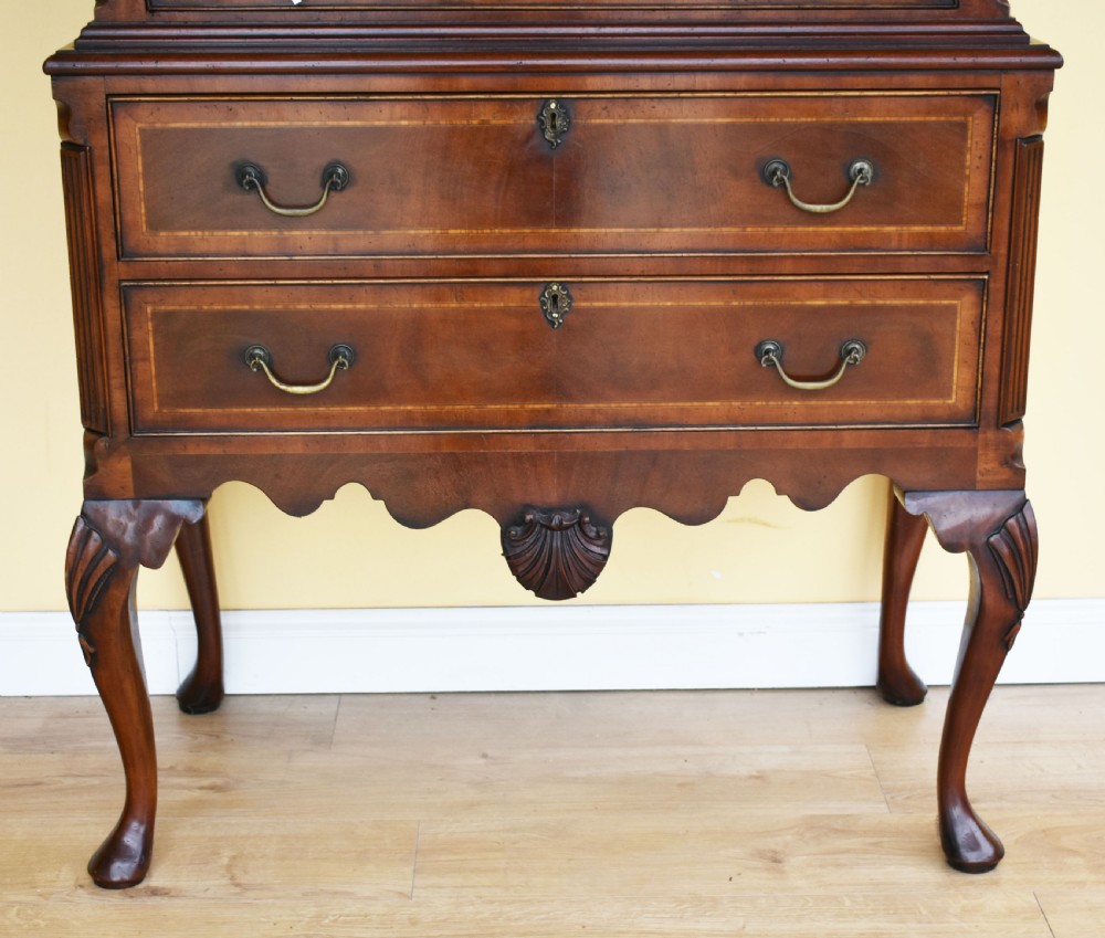 A Georgian style mahogany chest on stand featuring an openwork scrolled pediment, five crossbanded drawers with brass swan-neck handles, and cabriole legs ending in pad feet. View IV