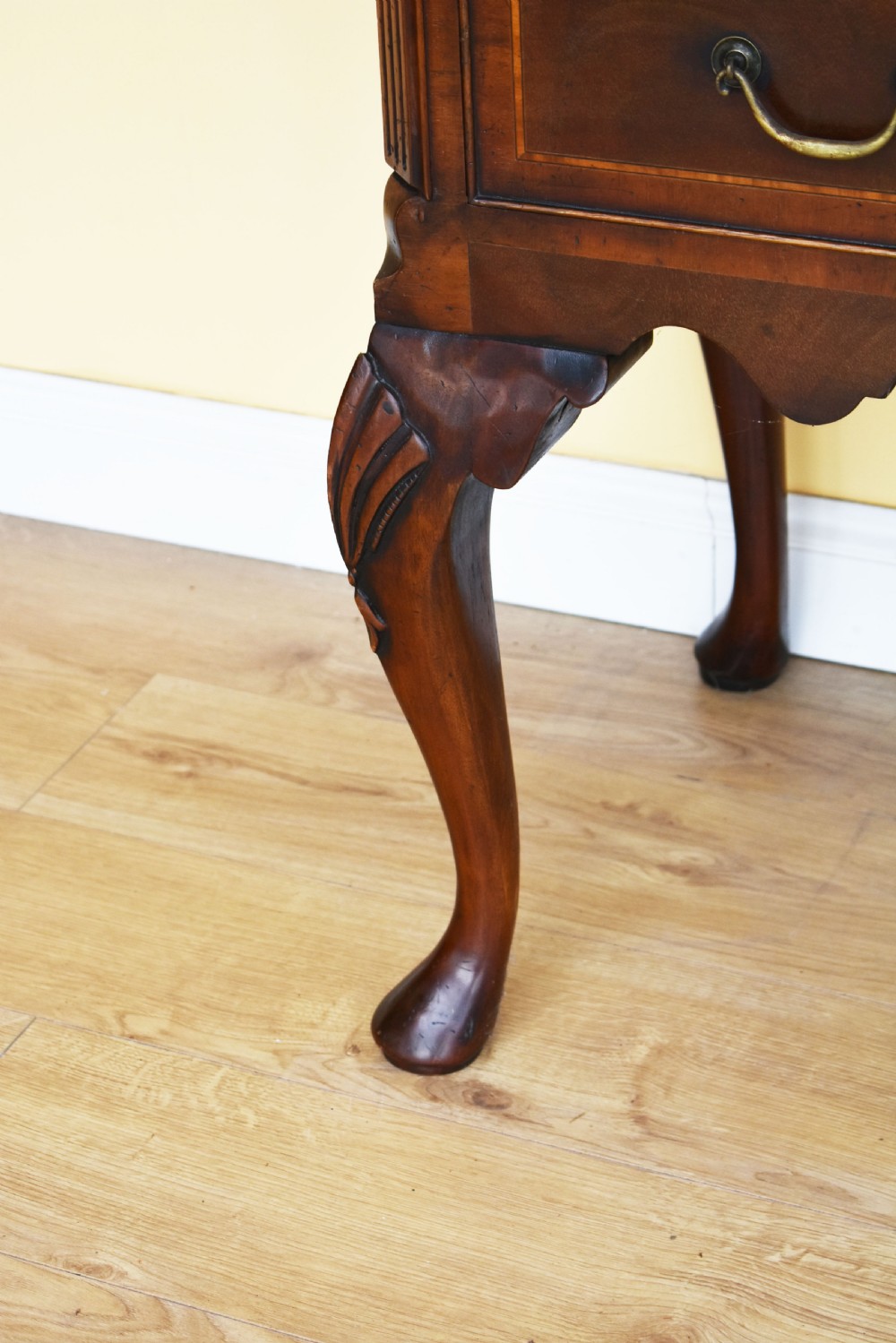 A Georgian style mahogany chest on stand featuring an openwork scrolled pediment, five crossbanded drawers with brass swan-neck handles, and cabriole legs ending in pad feet. View V