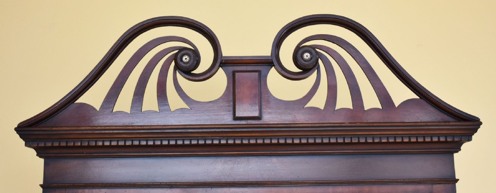 A Georgian style mahogany chest on stand featuring an openwork scrolled pediment, five crossbanded drawers with brass swan-neck handles, and cabriole legs ending in pad feet. View VI