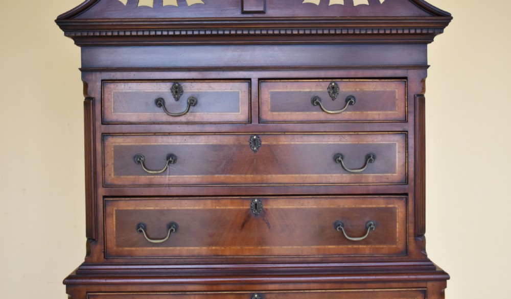 A Georgian style mahogany chest on stand featuring an openwork scrolled pediment, five crossbanded drawers with brass swan-neck handles, and cabriole legs ending in pad feet. View VII