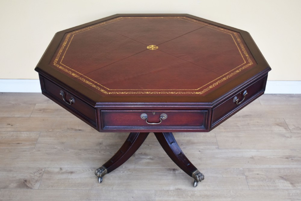 An octagonal Edwardian mahogany drum table featuring a leather inset top, drawers with brass handles, and a central pedestal with four splayed legs on brass castors. View III