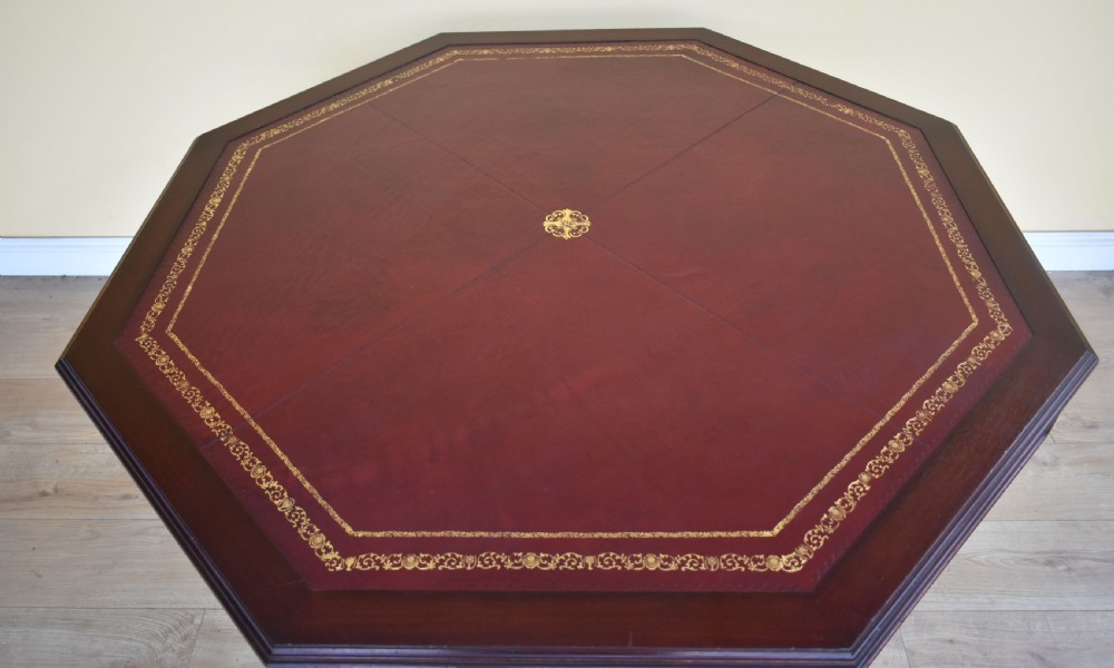 An octagonal Edwardian mahogany drum table featuring a leather inset top, drawers with brass handles, and a central pedestal with four splayed legs on brass castors. View V