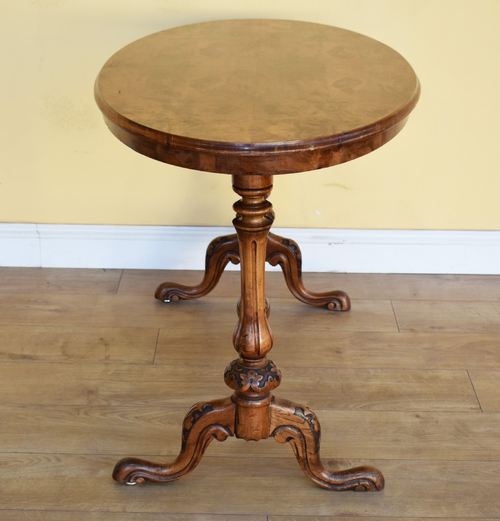 An oval Victorian burr walnut occasional table featuring carved turned uprights, a decorative stretcher, and carved cabriole legs. View IV