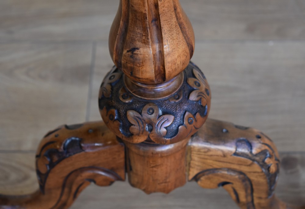 An oval Victorian burr walnut occasional table featuring carved turned uprights, a decorative stretcher, and carved cabriole legs. View V