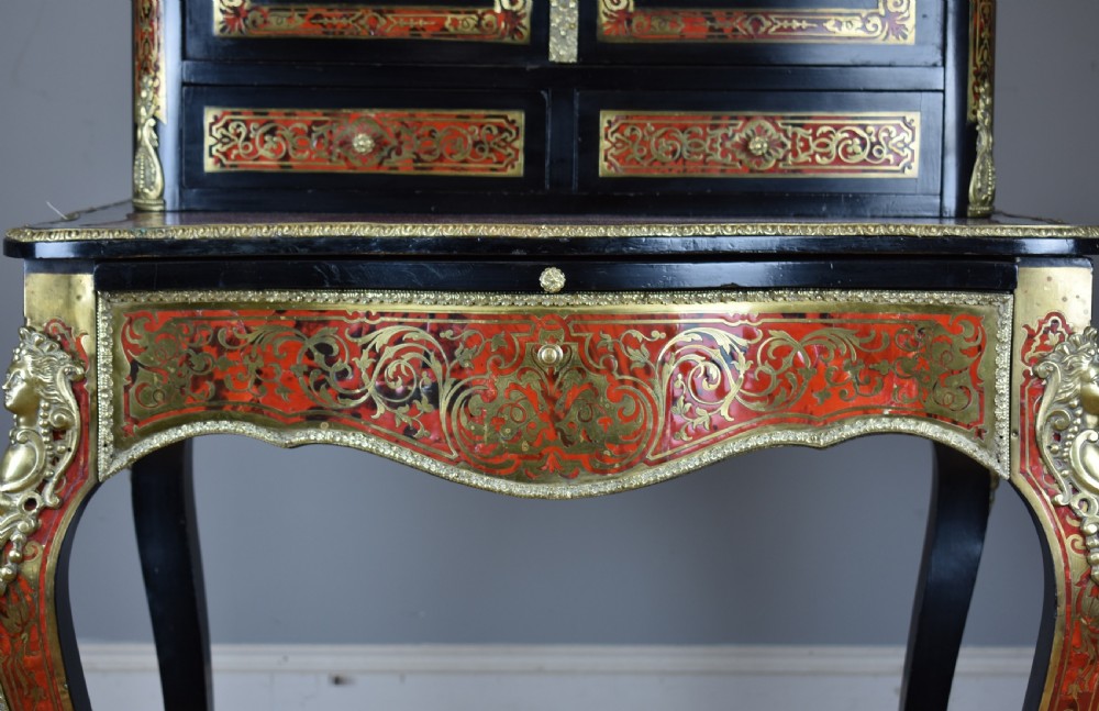 A 19th-century ebonised French bonheur du jour writing desk featuring red tortoiseshell and brass Boulle marquetry, cabriole legs, and gilt-bronze mounts. View X