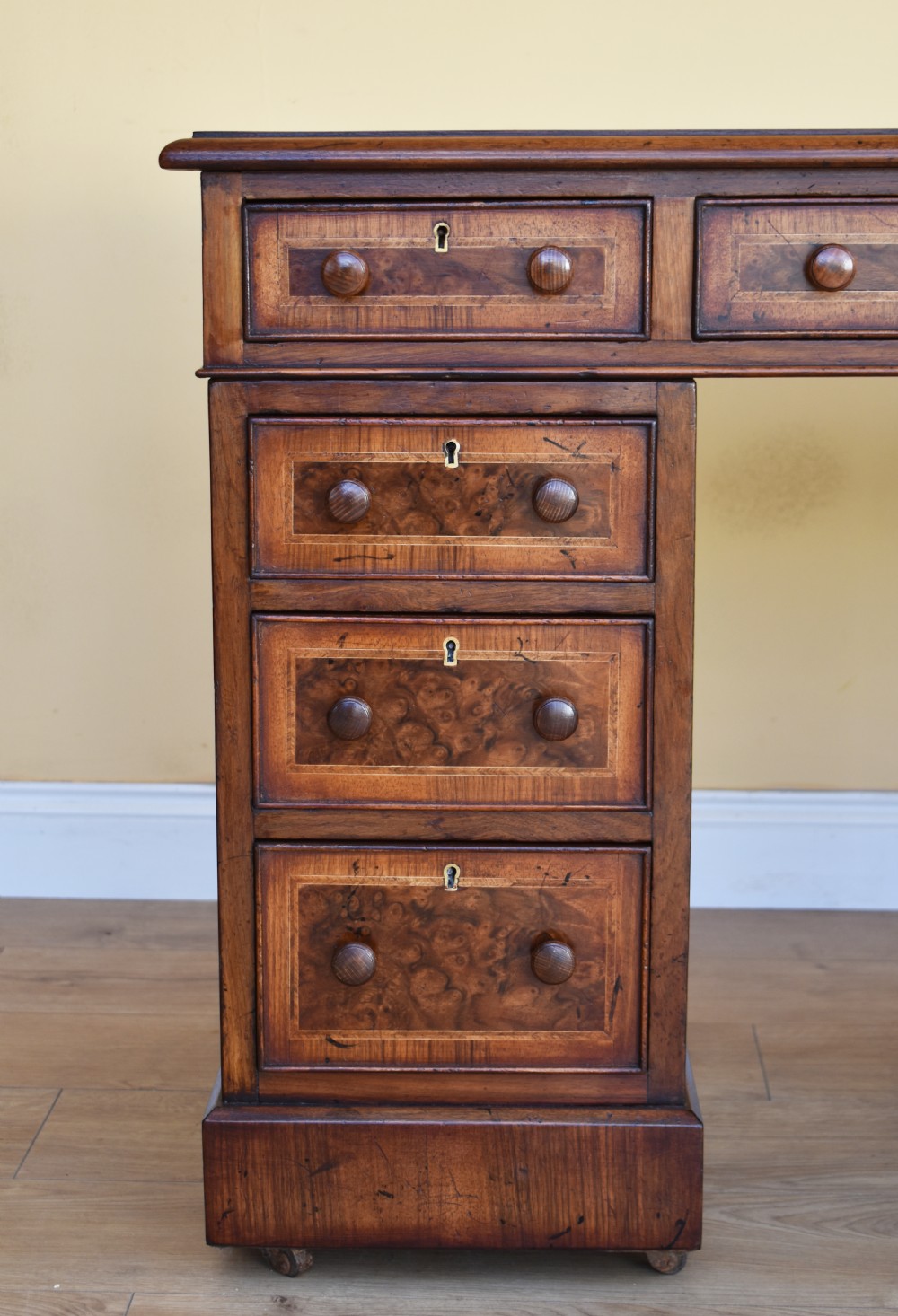 A nineteenth-century Victorian pedestal desk crafted from burr walnut featuring nine drawers with turned wooden handles and a leather writing top. View III