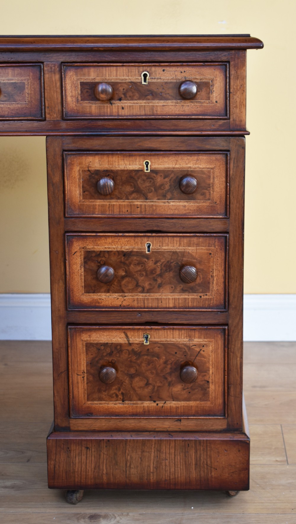 A nineteenth-century Victorian pedestal desk crafted from burr walnut featuring nine drawers with turned wooden handles and a leather writing top. View V