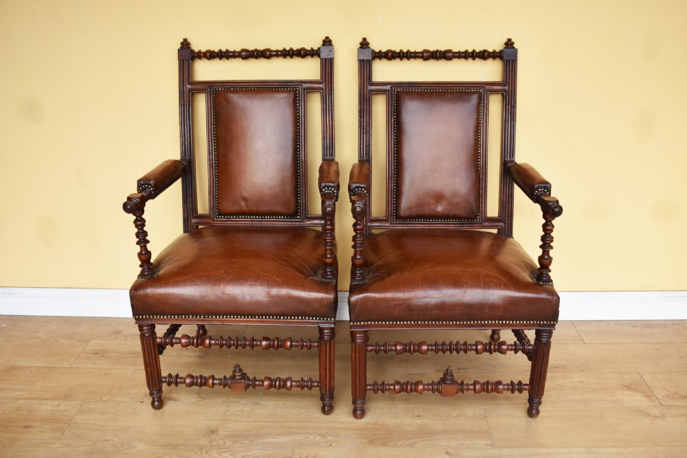A pair of 19th-century Victorian walnut Gothic Revival armchairs featuring bobbin-turned stretchers and warm brown leather upholstery with brass studding. View II