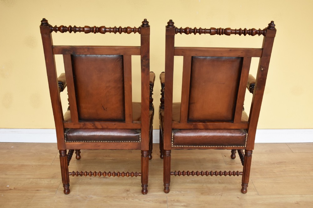 A pair of 19th-century Victorian walnut Gothic Revival armchairs featuring bobbin-turned stretchers and warm brown leather upholstery with brass studding. View III