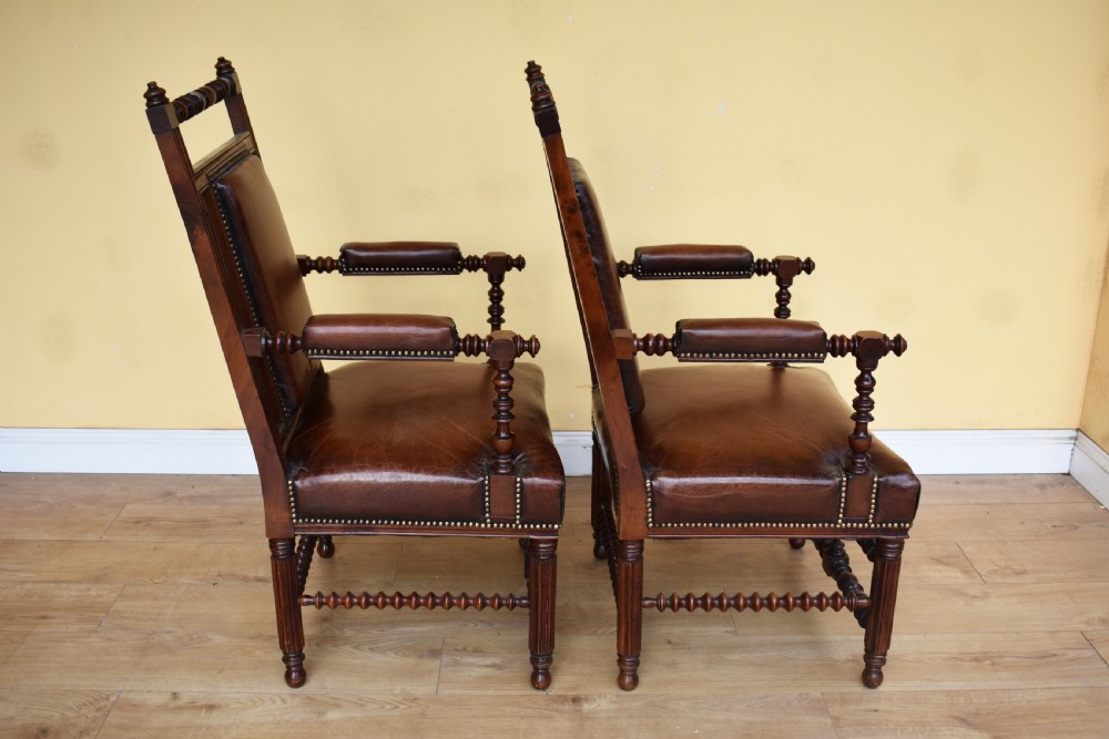 A pair of 19th-century Victorian walnut Gothic Revival armchairs featuring bobbin-turned stretchers and warm brown leather upholstery with brass studding. View IV