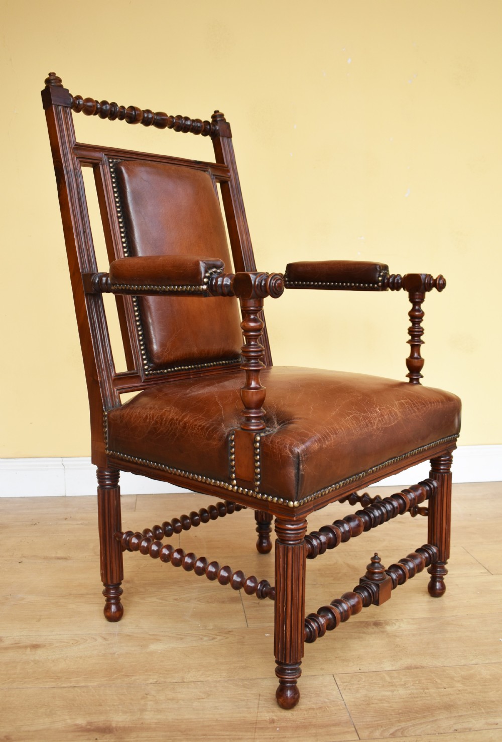 A pair of 19th-century Victorian walnut Gothic Revival armchairs featuring bobbin-turned stretchers and warm brown leather upholstery with brass studding. View VII