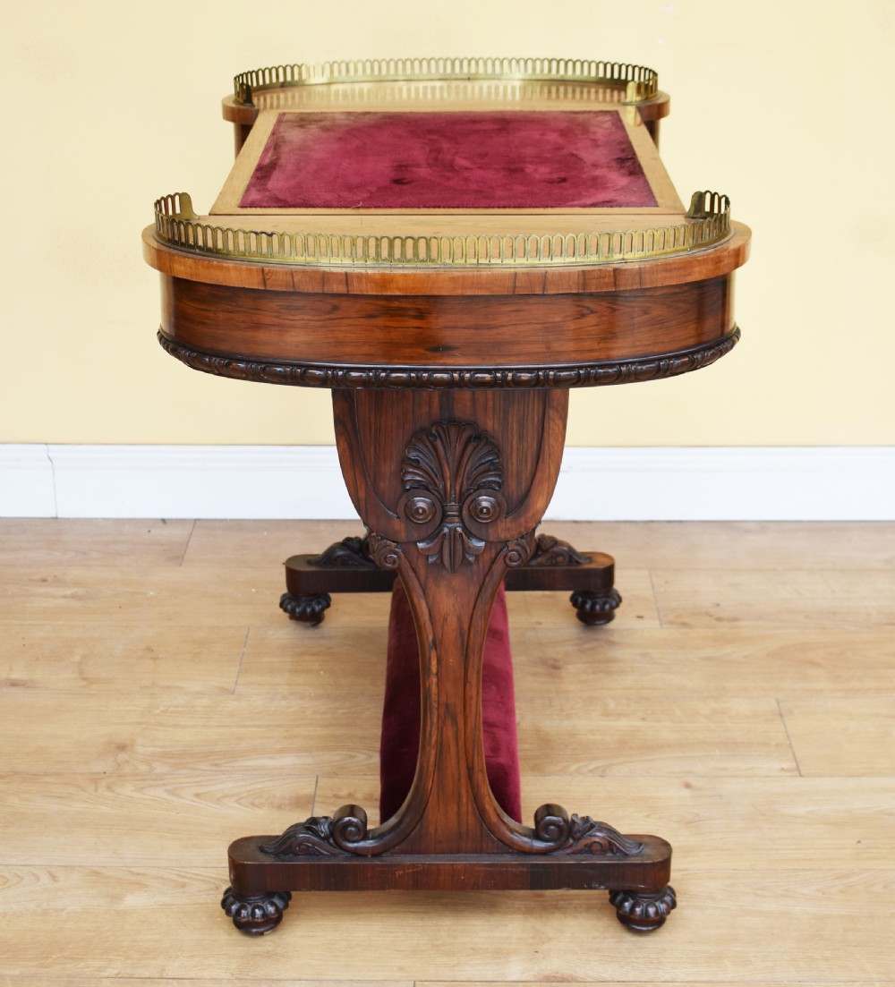 A 19th-century William IV rosewood writing table featuring an adjustable velvet-covered reading slope flanked by brass gallery rails on carved pedestal supports. View IX
