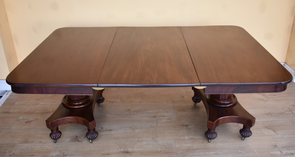 A 19th-century Regency mahogany extending dining table with twin octagonal pedestals, concave bases, reeded feet, and brass castors. View II