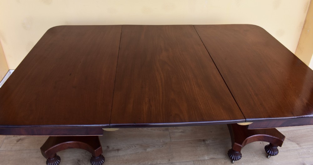 A 19th-century Regency mahogany extending dining table with twin octagonal pedestals, concave bases, reeded feet, and brass castors. View III