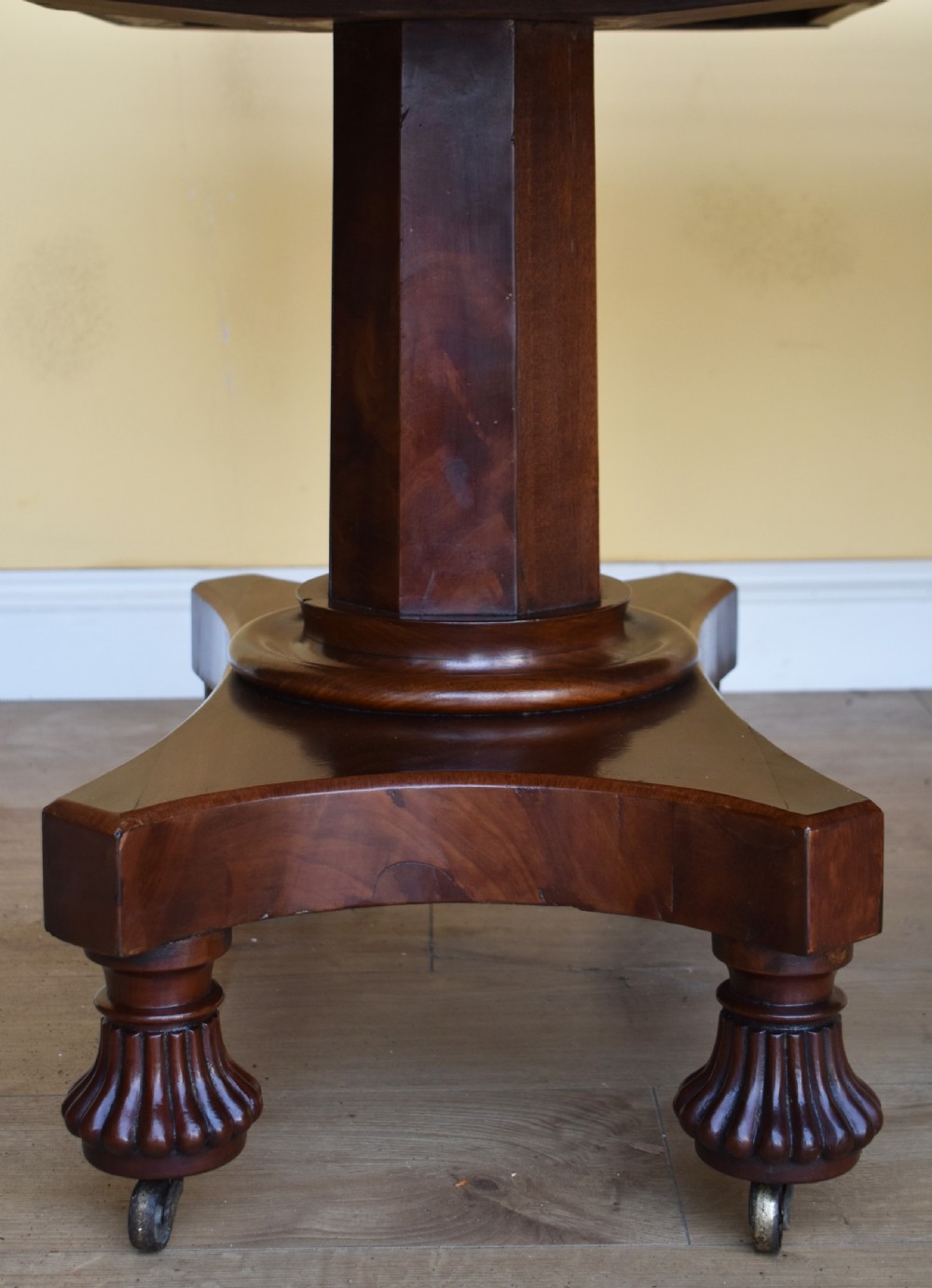 A 19th-century Regency mahogany extending dining table with twin octagonal pedestals, concave bases, reeded feet, and brass castors. View V