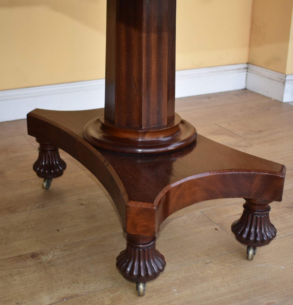 A 19th-century Regency mahogany extending dining table with twin octagonal pedestals, concave bases, reeded feet, and brass castors. View VII