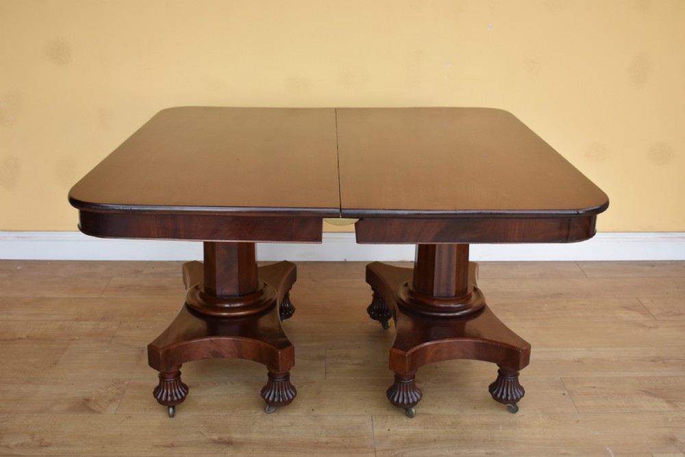 A 19th-century Regency mahogany extending dining table with twin octagonal pedestals, concave bases, reeded feet, and brass castors. View VIII