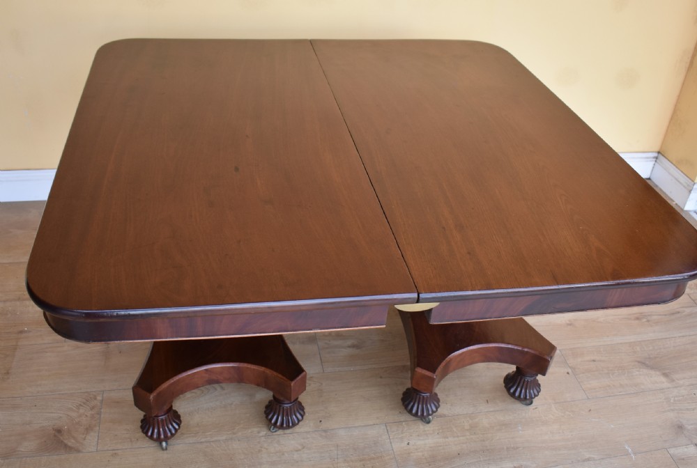 A 19th-century Regency mahogany extending dining table with twin octagonal pedestals, concave bases, reeded feet, and brass castors. View IX