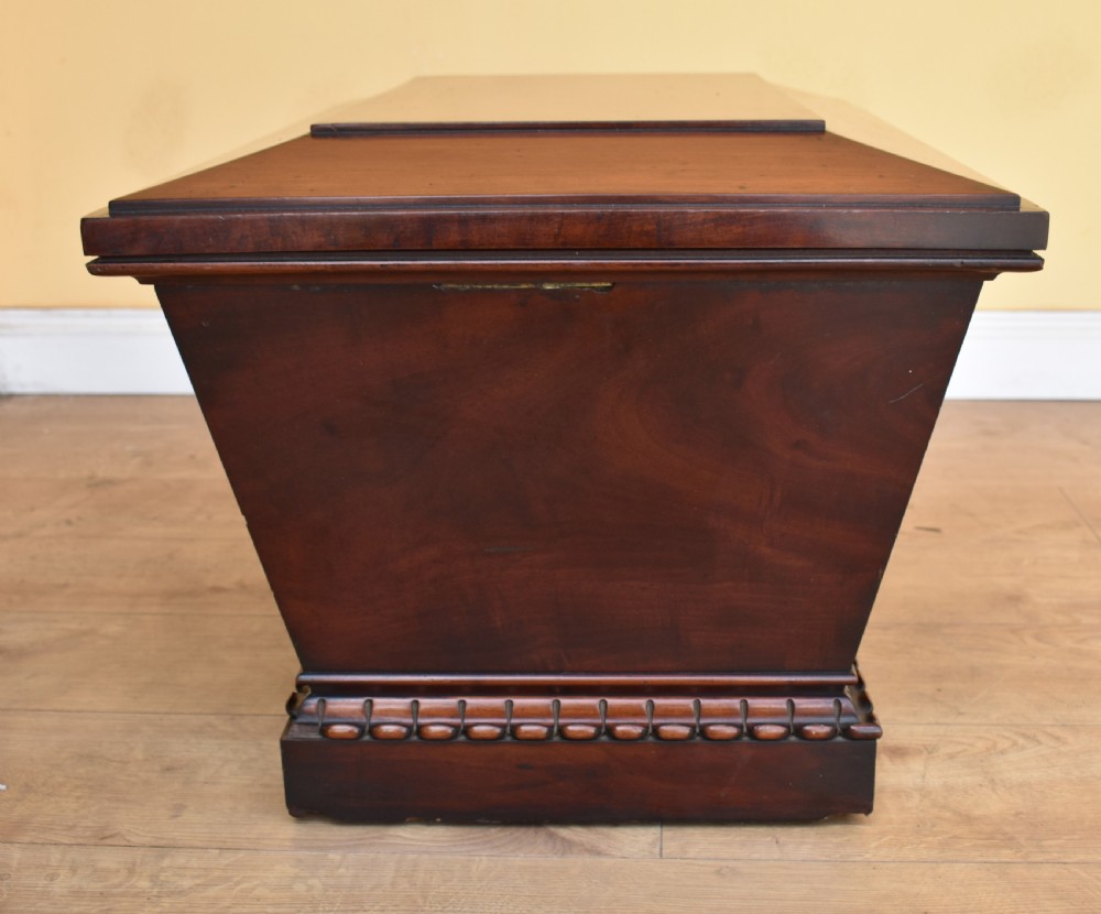 A 19th-century William IV sarcophagus-shaped mahogany wine cooler with a stepped lid and gadrooned plinth base. View VI