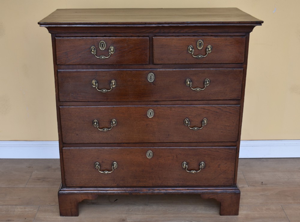 An 18th-century George III oak chest of drawers featuring a two over three drawer arrangement with brass handles and bracket feet. View II