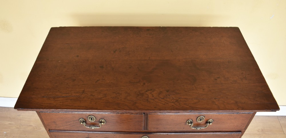 An 18th-century George III oak chest of drawers featuring a two over three drawer arrangement with brass handles and bracket feet. View III