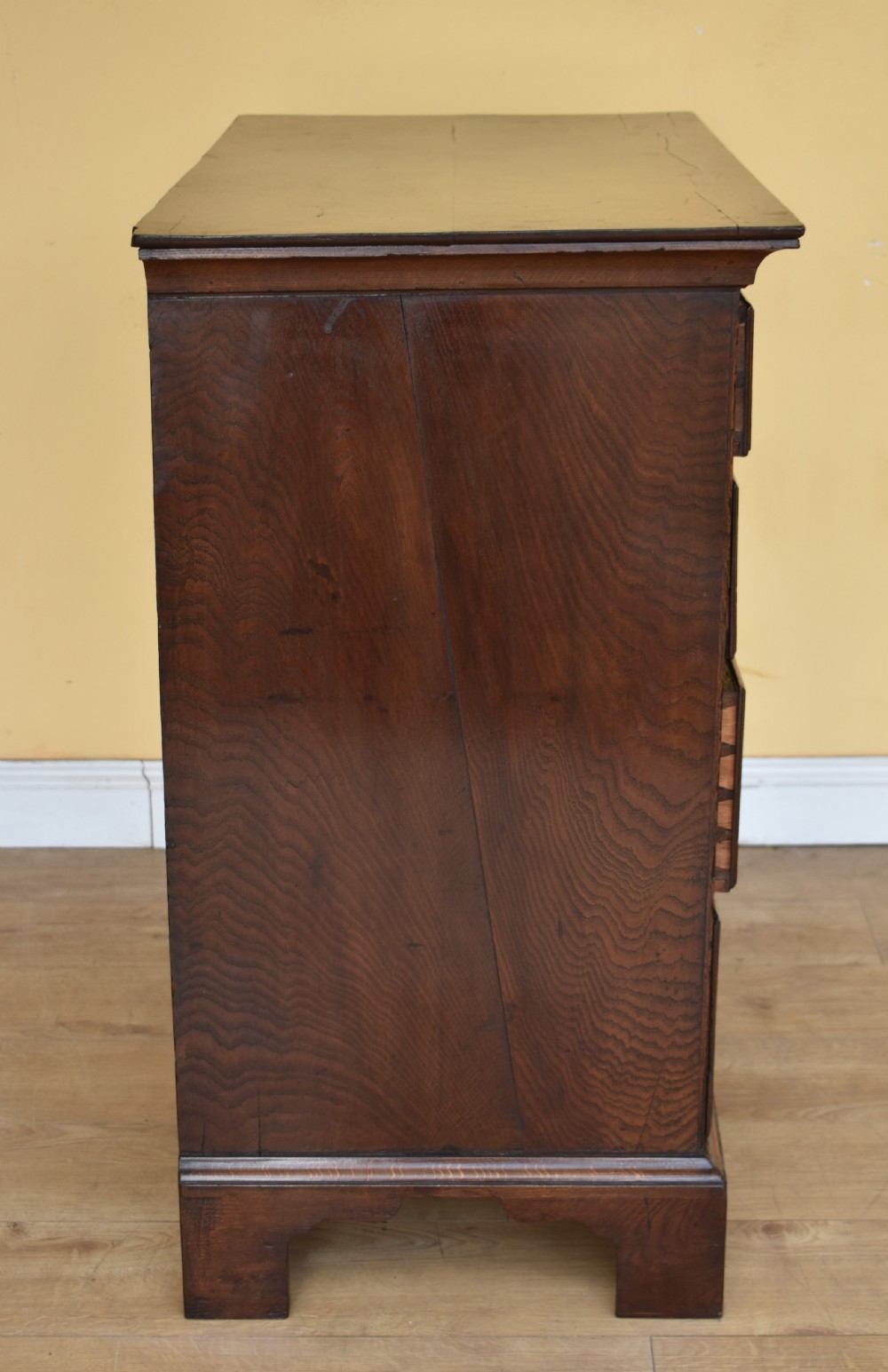An 18th-century George III oak chest of drawers featuring a two over three drawer arrangement with brass handles and bracket feet. View IV