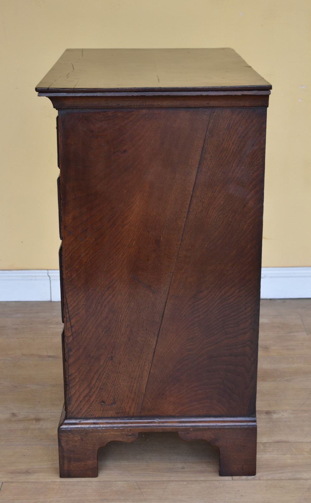 An 18th-century George III oak chest of drawers featuring a two over three drawer arrangement with brass handles and bracket feet. View V