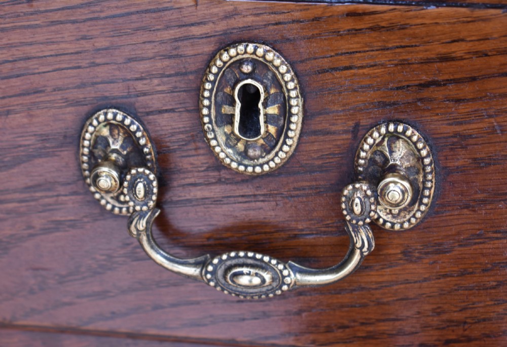 An 18th-century George III oak chest of drawers featuring a two over three drawer arrangement with brass handles and bracket feet. View VII