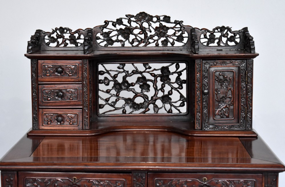 A 19th-century Chinese carved padouk wood desk featuring an intricate openwork gallery superstructure, frieze drawers, and cabriole legs ending in claw feet. View III