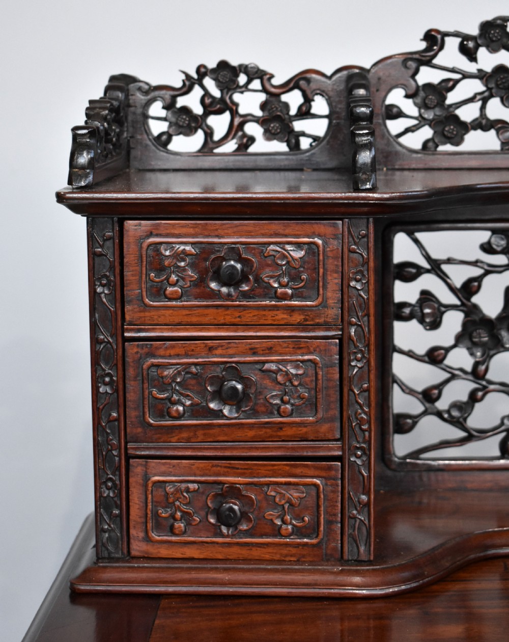A 19th-century Chinese carved padouk wood desk featuring an intricate openwork gallery superstructure, frieze drawers, and cabriole legs ending in claw feet. View IV