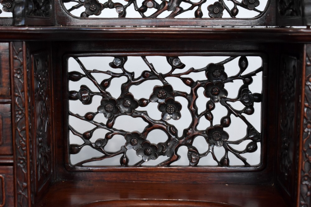 A 19th-century Chinese carved padouk wood desk featuring an intricate openwork gallery superstructure, frieze drawers, and cabriole legs ending in claw feet. View V