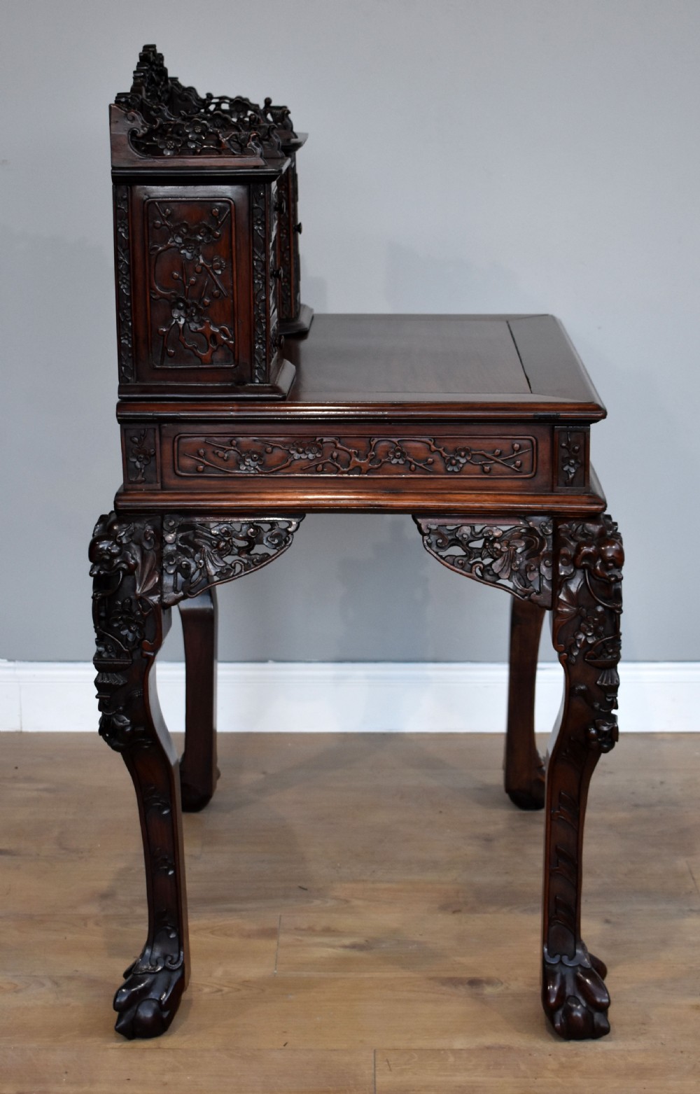 A 19th-century Chinese carved padouk wood desk featuring an intricate openwork gallery superstructure, frieze drawers, and cabriole legs ending in claw feet. View XI