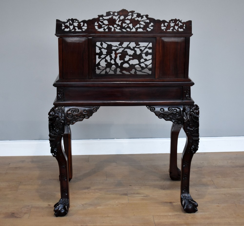 A 19th-century Chinese carved padouk wood desk featuring an intricate openwork gallery superstructure, frieze drawers, and cabriole legs ending in claw feet. View XII
