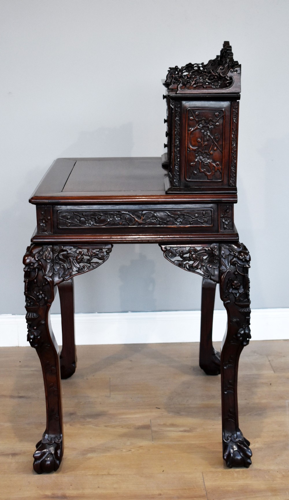 A 19th-century Chinese carved padouk wood desk featuring an intricate openwork gallery superstructure, frieze drawers, and cabriole legs ending in claw feet. View XIII