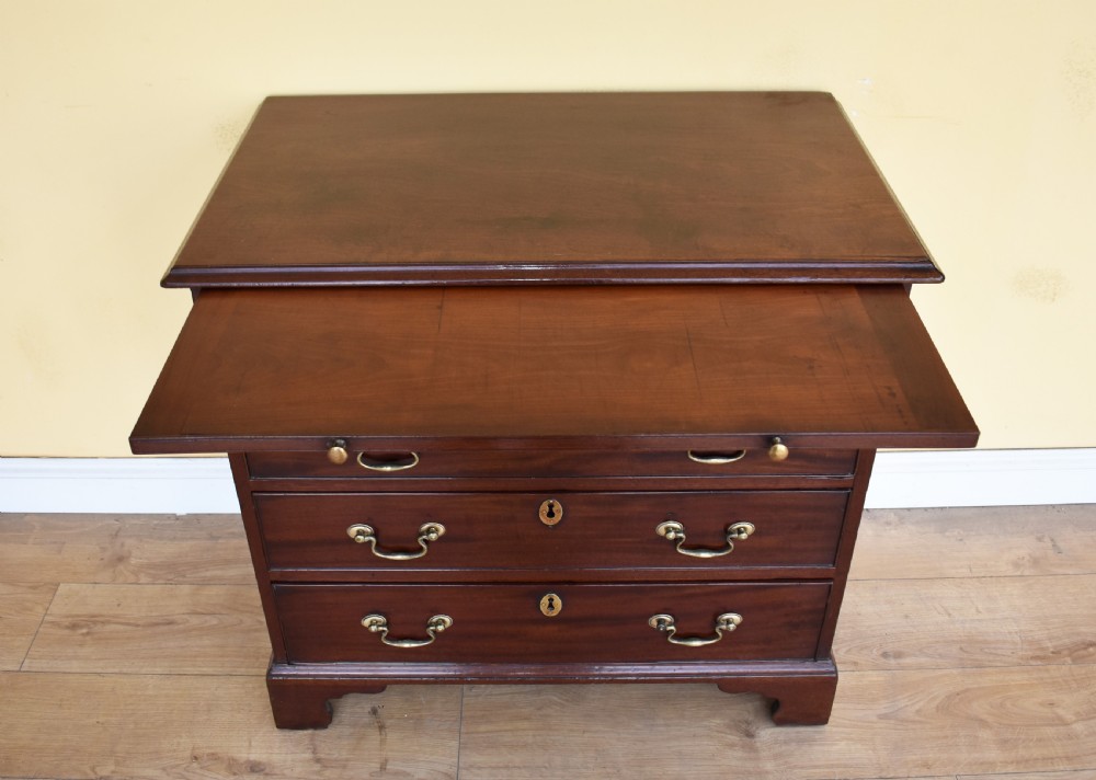 A George III mahogany chest of drawers featuring four graduated drawers, brass swan-neck handles, keyhole escutcheons, a brushing slide, and bracket feet. View IV