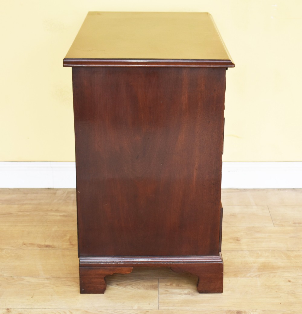 A George III mahogany chest of drawers featuring four graduated drawers, brass swan-neck handles, keyhole escutcheons, a brushing slide, and bracket feet. View V