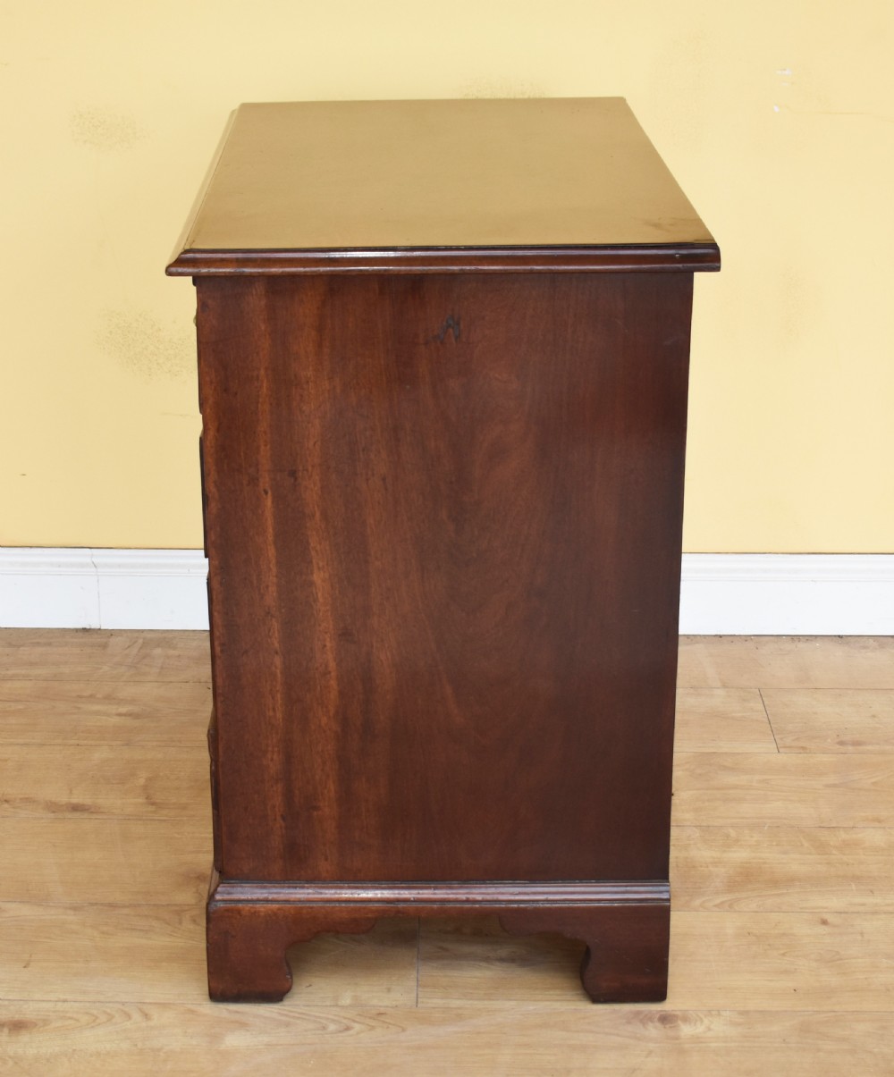 A George III mahogany chest of drawers featuring four graduated drawers, brass swan-neck handles, keyhole escutcheons, a brushing slide, and bracket feet. View VI