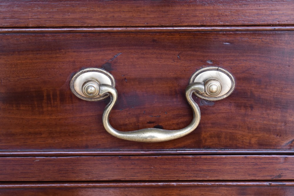 A George III mahogany chest of drawers featuring four graduated drawers, brass swan-neck handles, keyhole escutcheons, a brushing slide, and bracket feet. View VIII