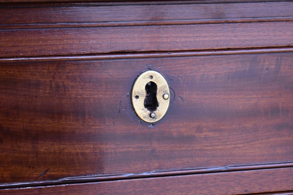 A George III mahogany chest of drawers featuring four graduated drawers, brass swan-neck handles, keyhole escutcheons, a brushing slide, and bracket feet. View IX