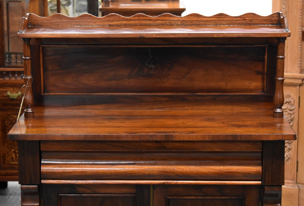 A Victorian rosewood chiffonier cabinet featuring twin panelled doors, a long frieze drawer, an upper gallery shelf with turned supports, and a solid plinth base. View II
