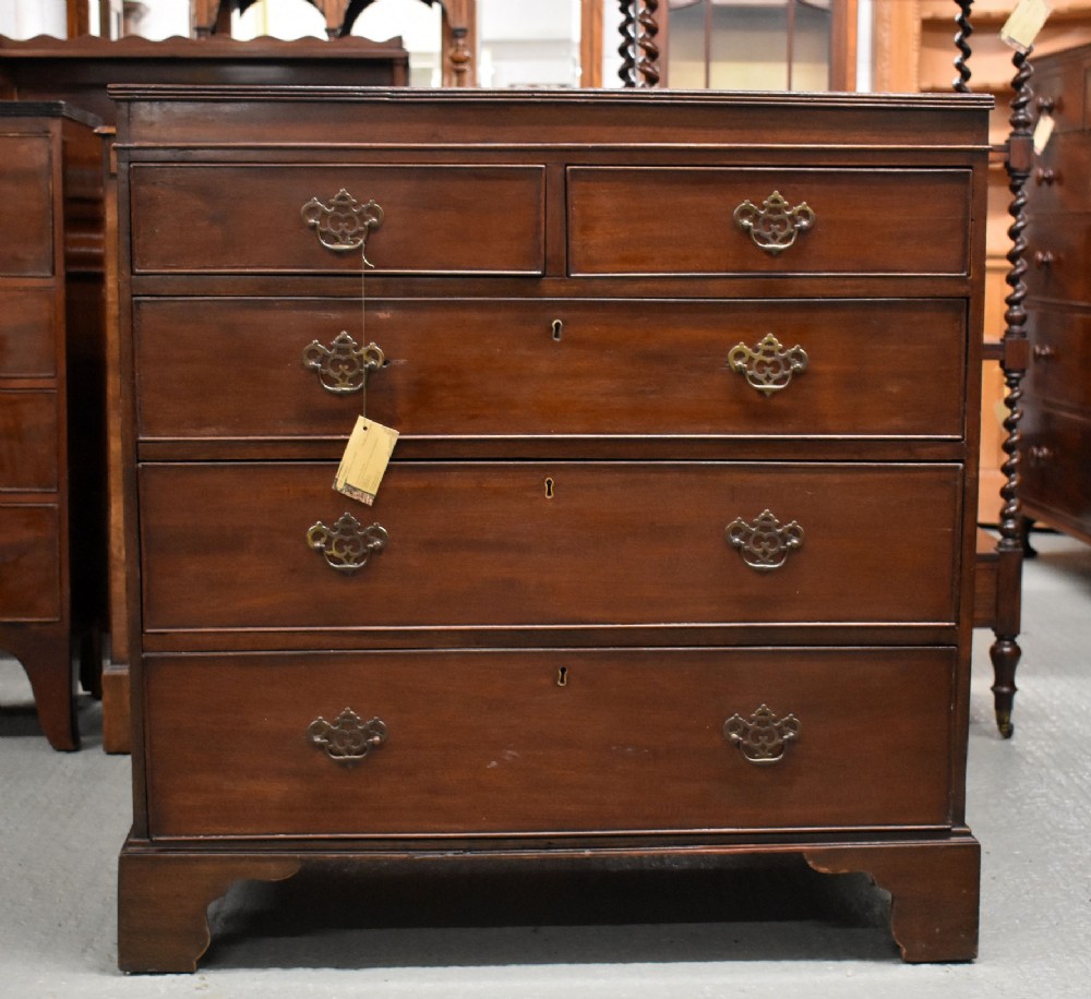 An antique mahogany chest of drawers featuring a two-over-three drawer configuration, brass swan-neck handles, keyhole escutcheons, and bracket feet.