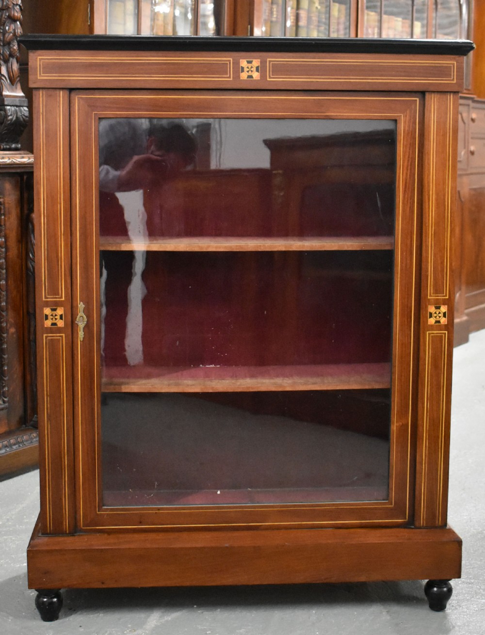 Victorian mahogany pier cabinet with a single glazed door, satinwood inlay borders, and turned black feet.
