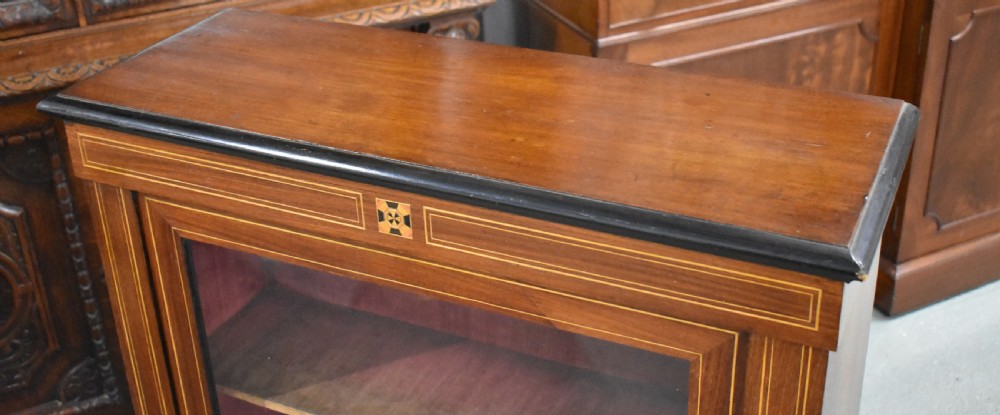 Victorian mahogany pier cabinet with a single glazed door, satinwood inlay borders, and turned black feet. View V
