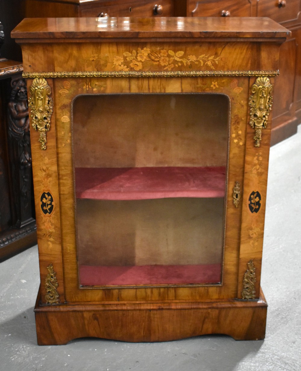 A Victorian walnut pier cabinet featuring floral marquetry inlays, decorative gilt ormolu mounts, and a glass door opening to velvet-lined shelves. View II