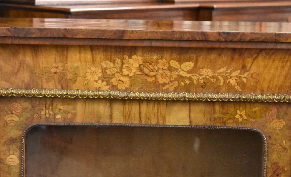 A Victorian walnut pier cabinet featuring floral marquetry inlays, decorative gilt ormolu mounts, and a glass door opening to velvet-lined shelves. View IV